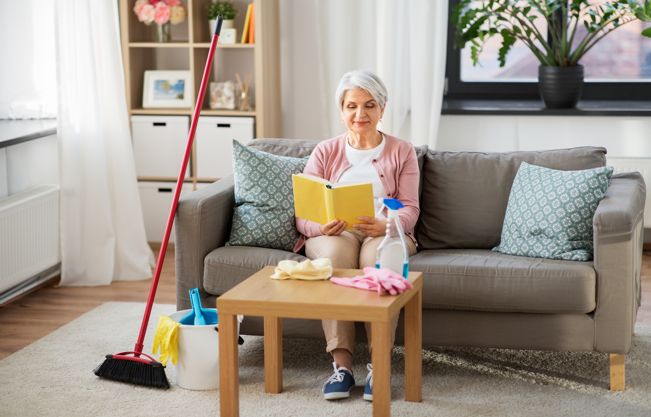 Senior Woman Reading Book after Cleaning House